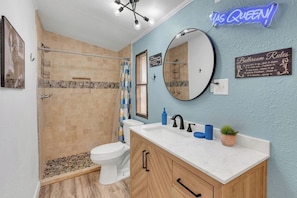 A bathroom with a shower, toilet, sink, and mirror. There are bathroom rules posted on the wall.