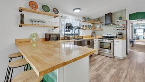 Une cuisine moderne avec un îlot central en bois, des appareils en acier inoxydable et des assiettes décoratives exposées sur des étagères.