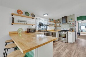 A modern kitchen with a wooden island, stainless steel appliances, and decorative plates on shelves.