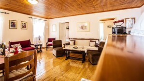Un salon chaleureux avec un plancher en bois, un canapé rouge, un canapé blanc, une table basse en bois et un fer à repasser rouge posé sur une table en bois.