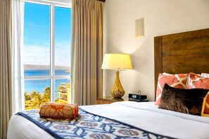 Une chambre d’hôtel avec un lit, une lampe, une table de chevet et une vue sur l’océan.