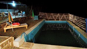 A swimming pool with a wooden deck and lounge chairs, surrounded by a wall of string lights. - Spacious 5-bedroom villa with swimming pool  WiFi and AC in lovely Alaverdi (Alaverdi)