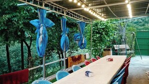 A covered outdoor dining area with a long table and blue chairs, surrounded by greenery. - Spacious 5-bedroom villa with swimming pool  WiFi and AC in lovely Alaverdi (Alaverdi)