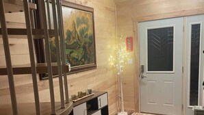 Ein Zimmer mit Holzboden, einem Etagenbett, einem Bild, einem Schrank und einer Tür.