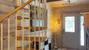 Ein Holzinnenraum mit einer Wendeltreppe, einer Tür mit Fenster und einer Stehlampe.