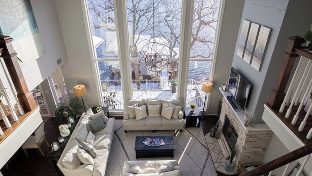 A spacious living area with a high ceiling, large windows, a fireplace, and a view of the outdoors. - Cimmaron Bay Retreat (Sunrise Beach)