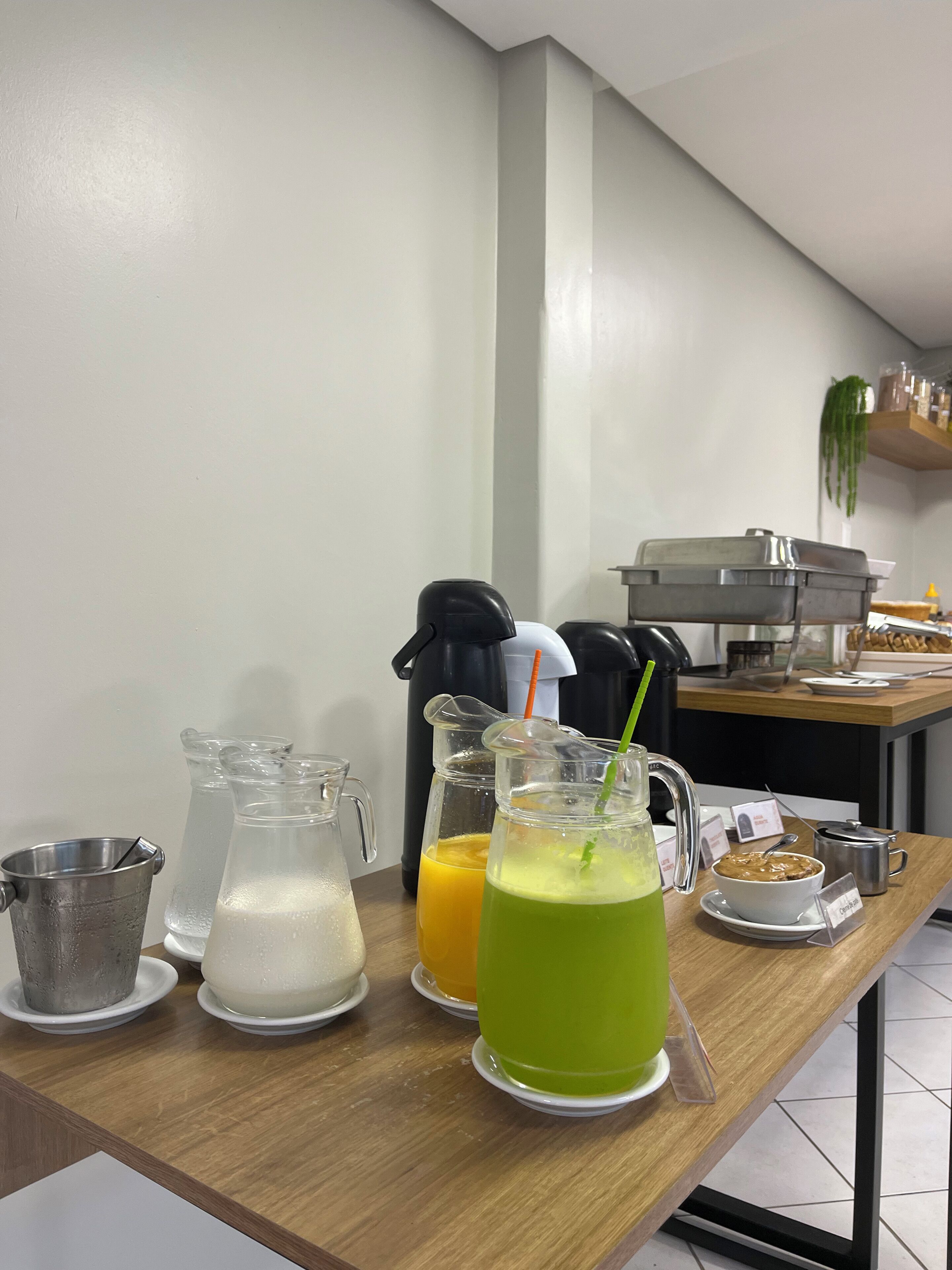 A breakfast bar with pitchers of beverages and a coffee maker.