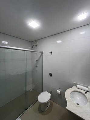 Ein modernes Badezimmer mit Duschkabine aus Glas, Toilette und Waschbecken mit Marmorplatte.