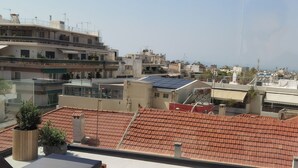 Une terrasse sur le toit, aménagée avec des meubles en bois, des plantes en pot et offrant une vue sur le paysage urbain.