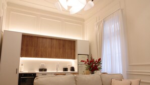 Une cuisine moderne avec des meubles blancs, un mur d’accent en bois et un four encastré.