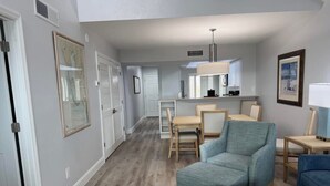 A spacious living area with a dining table and chairs, a sofa, and a kitchen in the background. - A charming two-bedroom beach front condo, Shell Island Beach Club, Sanibel. (Sanibel)