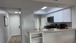 A modern kitchen with white cabinets, a microwave, and a countertop. - A charming two-bedroom beach front condo, Shell Island Beach Club, Sanibel. (Sanibel)