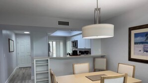A modern kitchen with white cabinets, a dining table with chairs, and a pendant light. - A charming two-bedroom beach front condo, Shell Island Beach Club, Sanibel. (Sanibel)