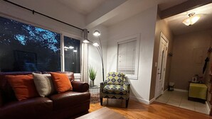 Un salon avec un canapé en cuir marron, un fauteuil à motifs, une table basse en bois et un lampadaire.