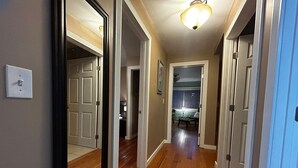 Un couloir avec un plancher en bois, des portes blanches et un luminaire au plafond.