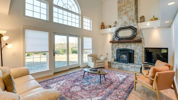 Amplia sala de estar con chimenea de piedra, ventanas grandes y un rincón de asientos acogedor.