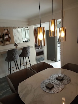 Una cocina moderna con comedor, con lámparas colgantes, un refrigerador y un conjunto de asientos.