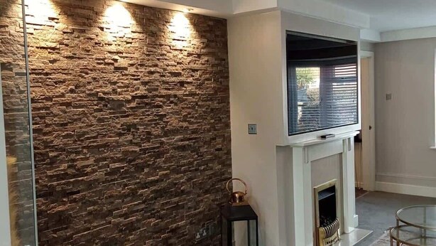 A modern living room with a stone wall, a fireplace, and a glass coffee table.