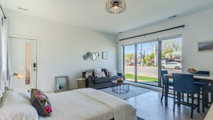 Ein modernes Schlafzimmer mit einem großen Bett, einer Couch, einer Essecke und Blick auf die Straße.