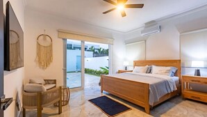 A bedroom with a wooden bed, a desk, a chair, and a large window. - Villa Valentina Oceanfront Bliss (Sosúa)