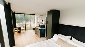 Un dormitorio moderno con una cama grande, un escritorio pequeño y vistas al exterior.