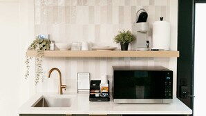 Una cocina moderna con microondas integrado, un lavamanos y un mueble pequeño.