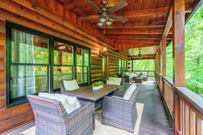 A covered porch with wicker furniture, large windows, and a ceiling fan.
