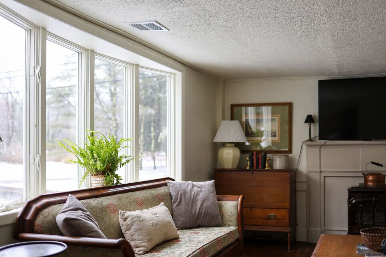 A cozy living room with a sofa, a side table, a lamp, a television, and a fireplace.