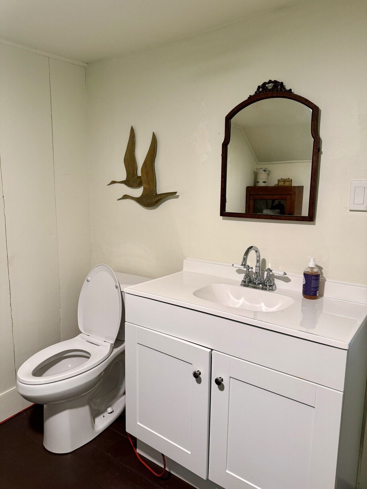 Une salle de bain comprenant des toilettes, un lavabo, un meuble de rangement, un miroir et des éléments décoratifs sur les murs.
