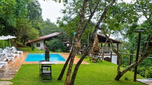 A pool area with a wooden deck, lounge chairs, and a small table.