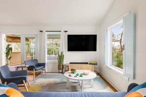Relax in this stylish living room with a large flat-screen TV, round coffee table, and comfortable armchairs.