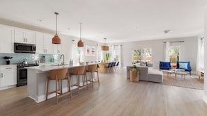 A modern kitchen with a central island, bar stools, and pendant lighting.