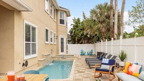 A backyard with a swimming pool, outdoor seating, and a patio area.