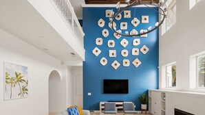 A living room with a blue accent wall, a flat-screen TV, a fireplace, and a seating area with a sofa and chairs.