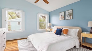 A bedroom with a bed, two windows, a nightstand, a lamp, and a ceiling fan. - Beach Bungalow 1blck to Beach w/ Hot Tub & Game Room Haven Grove by Avantstay (St. Augustine)