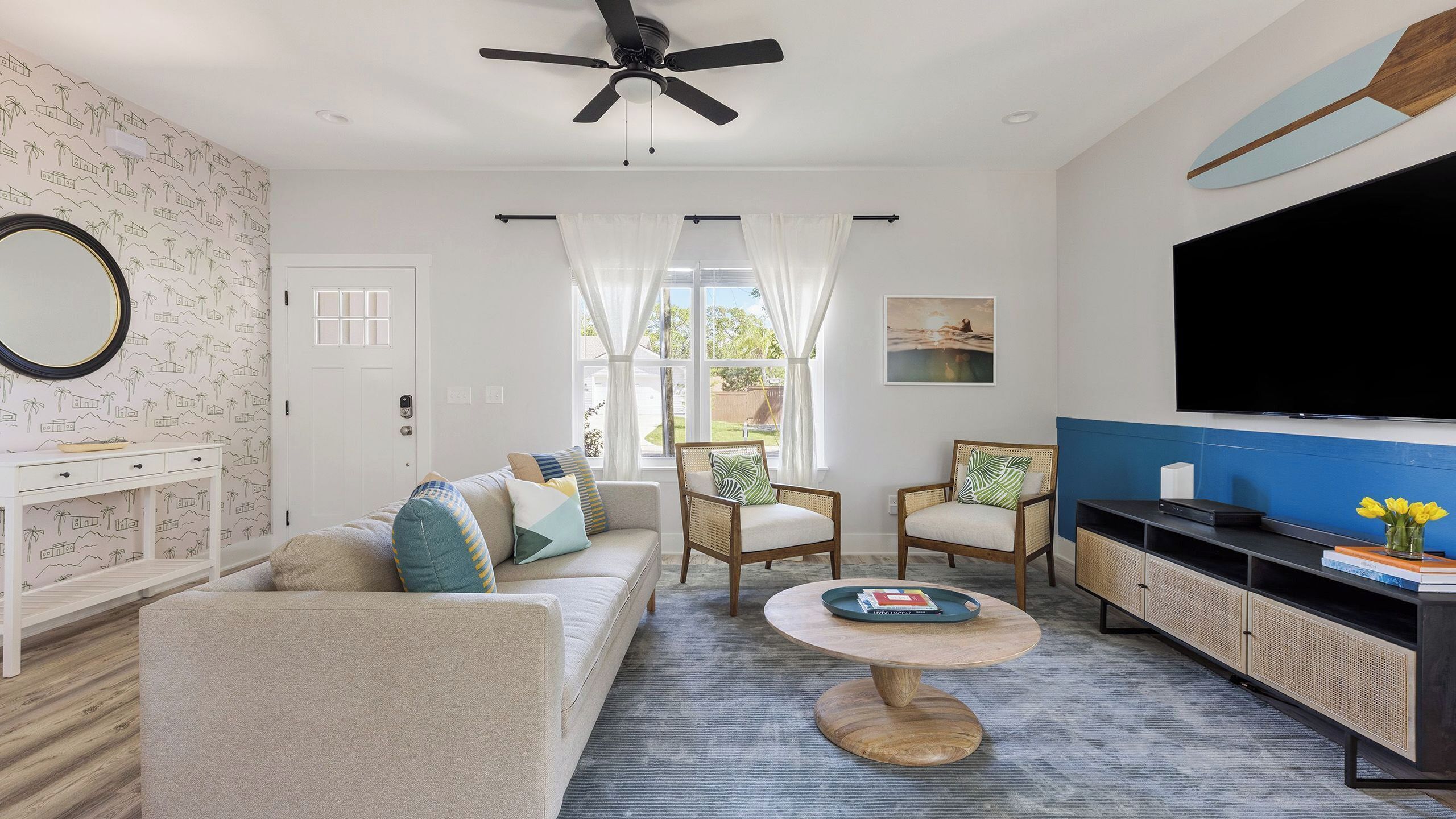 A living room with a sofa, chairs, a coffee table, a TV, and a ceiling fan.