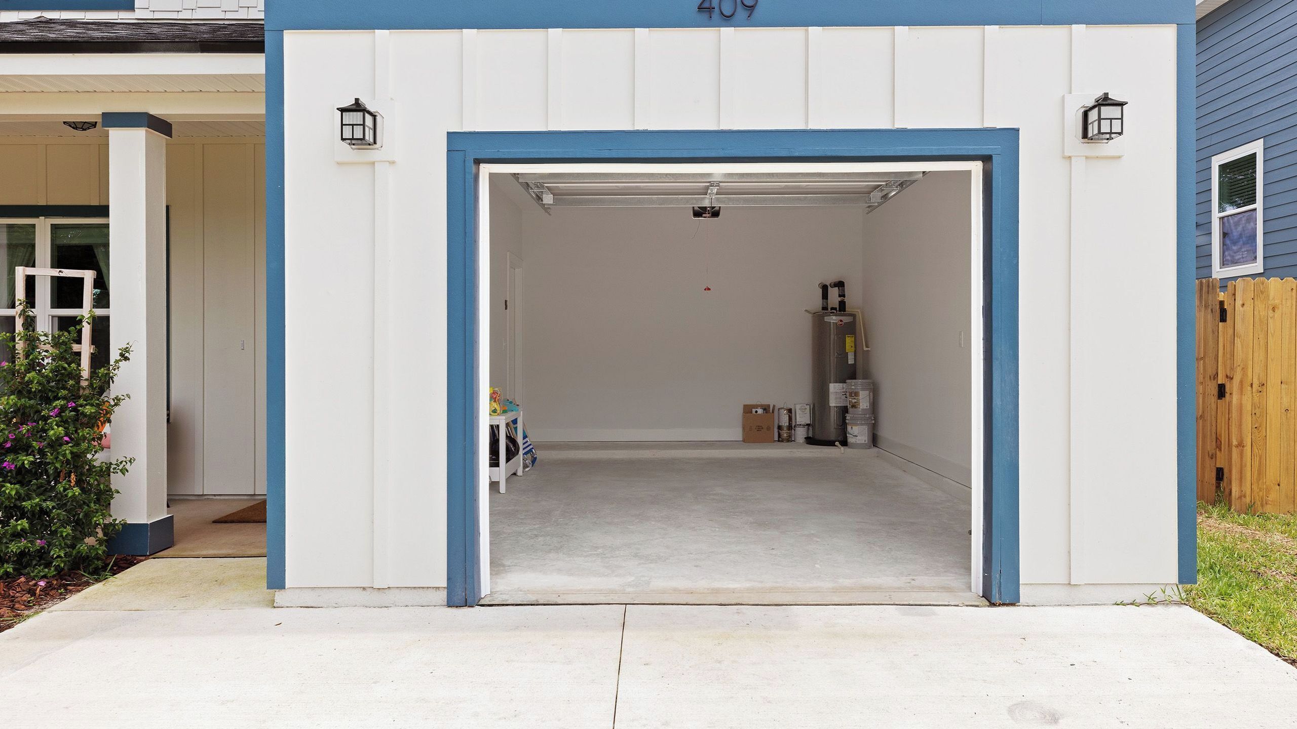 En garage med en blå dør, en varmtvandsbeholder og et lille bord med ting på.