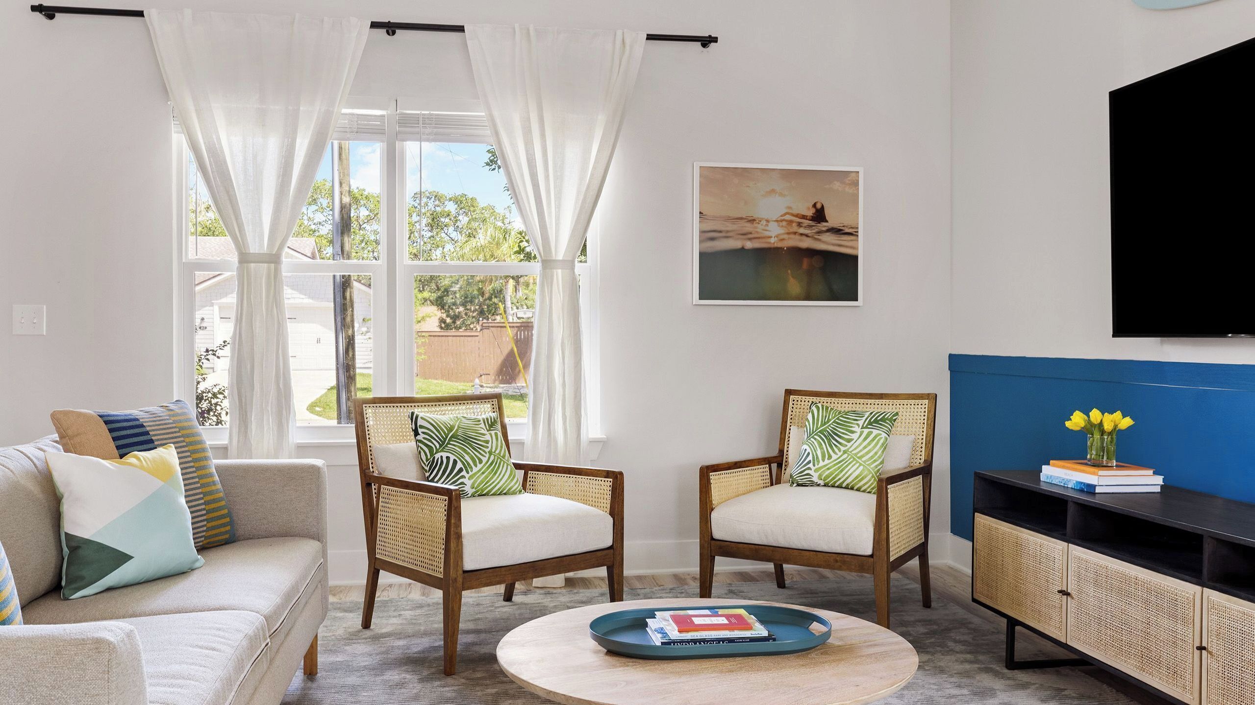 A living room with a sofa, two chairs, a coffee table, a TV, and a bookshelf.