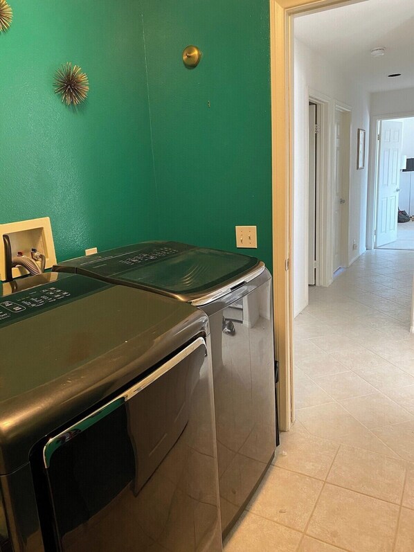 A laundry room with a green wall, a washing machine, and a dryer.