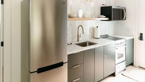 Une cuisine moderne équipée d’un réfrigérateur en acier inoxydable, d’un four à micro-ondes et d’un évier.