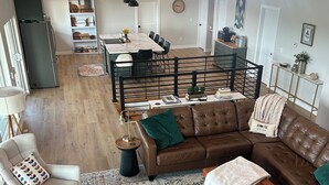 A spacious living area with a brown leather sofa, a patterned rug, and a dining table.