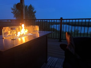 A deck with a fire feature, a railing, and a view of a body of water.