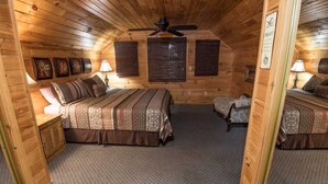 Una camera da letto accogliente in legno con due letti, una ventola a soffitto e un piccolo angolo salotto.