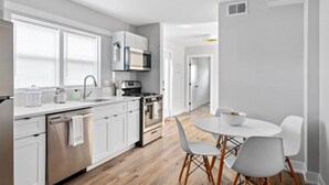 A modern kitchen with white cabinets, a built-in oven, and a dining area with a white table and chairs. - Modern Renovated Suite in Riverside  (Riverside)