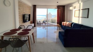 A modern living room with a balcony, a dining area, and a sofa. - Golden Seaview Apartment  (Sarande)