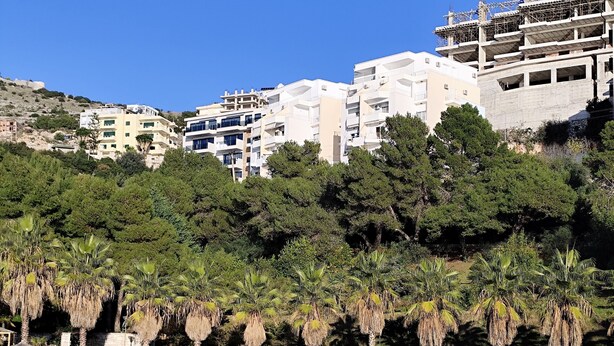 A coastal area with buildings, trees, and a waterfront. - Golden Seaview Apartment  (Sarande)