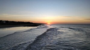 Egy naplementés strand, ahol a hullámok a partig érnek.