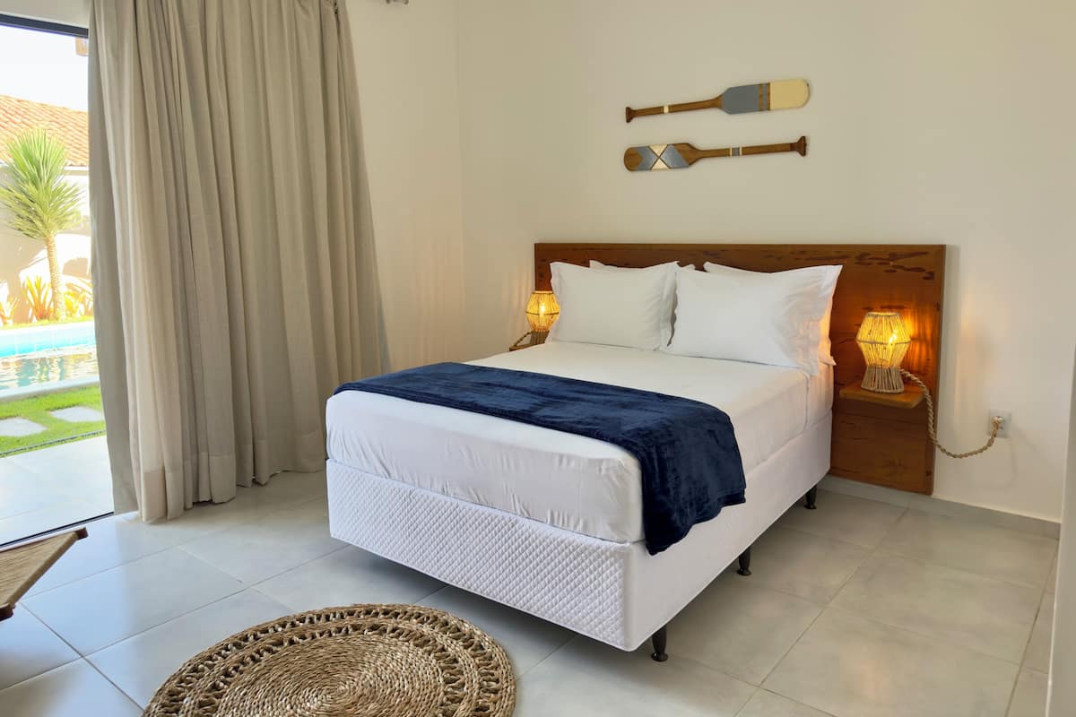 A neatly made bed with a blue blanket, two bedside lamps, and a headboard with wall-mounted bathtubs.
