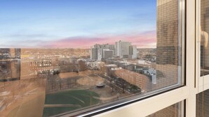 Un immeuble de grande hauteur offrant une vue sur le paysage urbain et un parc situé en contrebas.