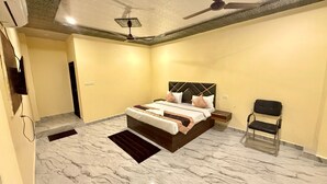 Ein Schlafzimmer mit einem Bett, einem Sessel, einem Nachttisch, einem Deckenventilator und einem an der Wand befestigten Fernseher.